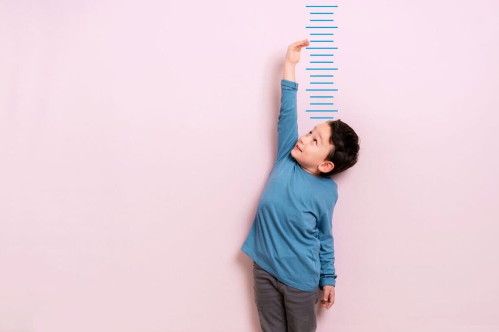 Top Canadian Stocks to Buy for Growth in 2026 Child measures his height on wall. He is growing taller.